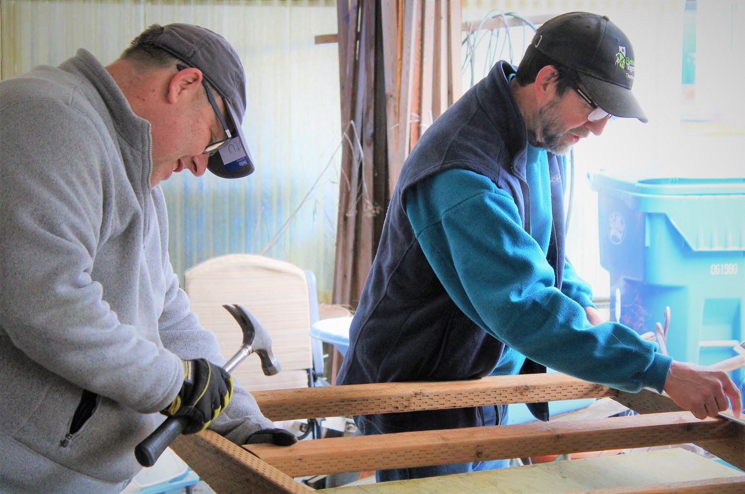 Stu Hemmings, using a hammer, and Bruce as they work on the wheelchair ramp framework.